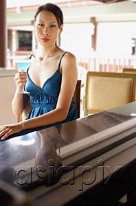 AsiaPix - Woman sitting at bar counter, holding cocktail, looking at camera