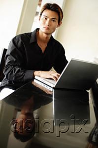 AsiaPix - Man using laptop, looking at camera