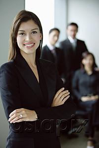 AsiaPix - Businesswoman standing with arms crossed, smiling, people in the background