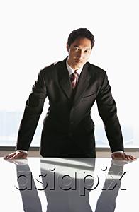 AsiaPix - Businessman leaning on table, looking at camera