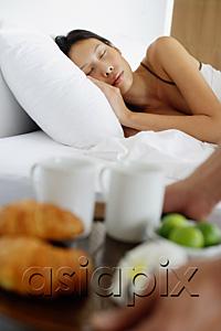 AsiaPix - Woman sleeping in bed, man setting down breakfast tray