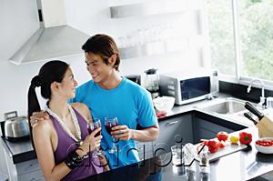 AsiaPix - Couple standing in kitchen, holding wine glasses