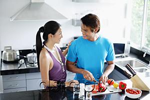 AsiaPix - Couple standing in kitchen, man chopping vegetables