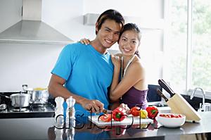 AsiaPix - Couple standing in kitchen, looking at camera, woman embracing man