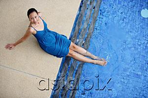 AsiaPix - Young woman sitting by swimming pool, feet in water, smiling at camera
