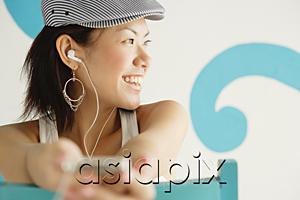 AsiaPix - Young woman wearing beret, listening to MP3 player, looking away, smiling