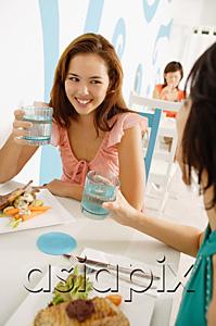 AsiaPix - Young women in cafe, having lunch, holding glasses of water