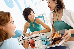 AsiaPix - Young women talking over drinks in cafe, one woman holding book