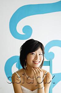AsiaPix - Young woman sitting on chair, looking at camera, hand on chin