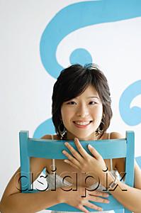 AsiaPix - Young woman sitting on chair, smiling at camera