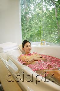 AsiaPix - Woman lying in bath tub, flowers floating in water