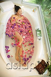 AsiaPix - Woman taking a bath, flowers floating in water, high angle view