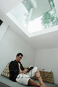 AsiaPix - Man sitting at home, reading a book