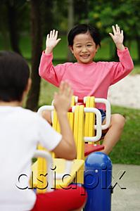 AsiaPix - Two girls on a seesaw, raising their hands