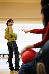 AsiaPix - Three women at a bowling alley, one woman with bowling ball, looking over shoulder