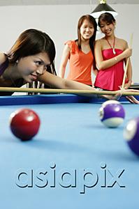 AsiaPix - Woman holding pool cue, aiming, women watching in the background