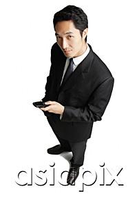AsiaPix - Businessman with mobile phone, looking at camera