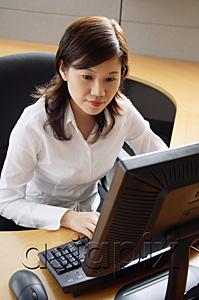 AsiaPix - Businesswoman sitting in office cubicle, looking at computer