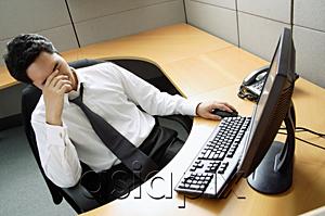 AsiaPix - Businessman sitting at desk, hand covering face
