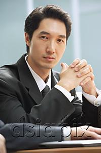 AsiaPix - Businessman looking at camera, hands clasped