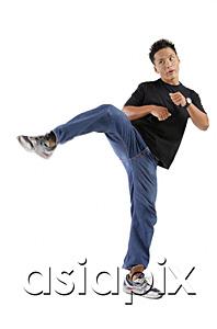 AsiaPix - Young man standing on one leg, kicking