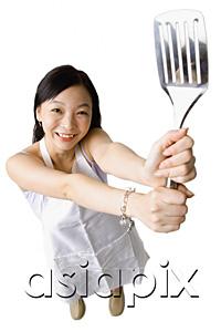 AsiaPix - Woman holding up kitchen utensil