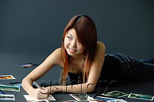 AsiaPix - Woman lying on floor, writing on backs of photographs