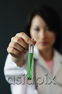 AsiaPix - Doctor holding test tube filled with green liquid, selective focus