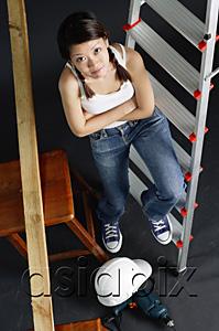 AsiaPix - Young woman sitting on ladder, arms crossed, looking at camera