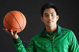 AsiaPix - Young man wearing green tracksuit jacket, holding basketball