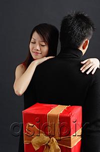 AsiaPix - Man holding gift behind his back, woman embracing him