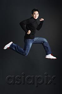AsiaPix - Young man dressed in black jumping and smiling at camera