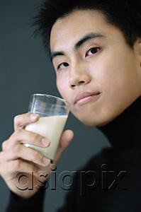 AsiaPix - Young man holding glass of milk, looking at camera