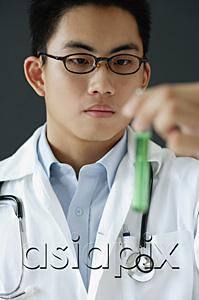 AsiaPix - Doctor holding test tube filled with green liquid