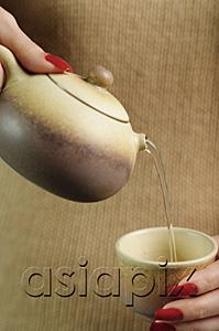 AsiaPix - Woman holding teapot, pouring tea