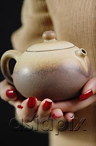 AsiaPix - Close up of womans hands holding tea pot