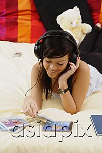 AsiaPix - Girl lying on bed, listening to headphones
