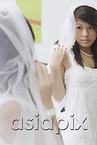 AsiaPix - Young woman in white dress and veil, looking at herself in mirror