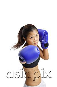 AsiaPix - Young woman wearing boxing gloves, looking at camera