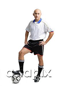AsiaPix - Young man wearing soccer uniform, standing with one leg on ball