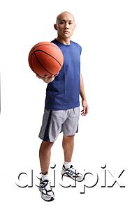 AsiaPix - Young man standing, holding basketball