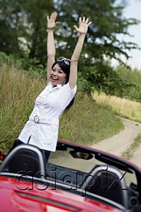 AsiaPix - Woman standing in red sports car with arms raised