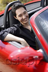 AsiaPix - Man sitting in red convertible car, smiling