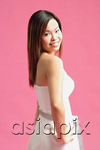 AsiaPix - Woman standing against pink background, hand on hip
