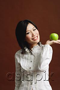 AsiaPix - Woman holding green apple in palm of hand