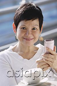 AsiaPix - Mature woman with mobile phone, looking at camera