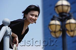 AsiaPix - Woman leaning over railing, smiling at camera