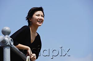 AsiaPix - Woman leaning on railing, smiling, looking away