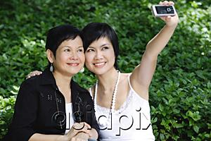 AsiaPix - Women side by side, smiling, taking a picture with mobile phone