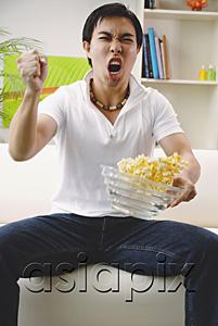 AsiaPix - Man holding bowl of popcorn, making a fist